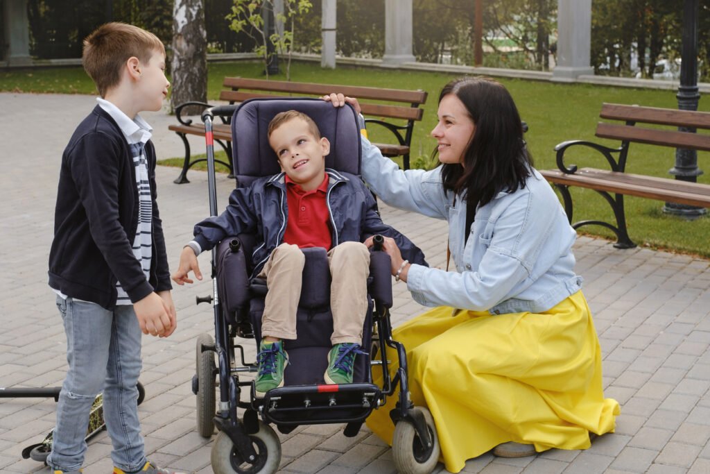 Betreuungssituation im Park in Bochum mit einem Kind im Rollstuhl und zwei weiteren Personen